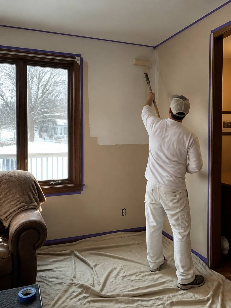Interior wall being professionally painted with the floor protected