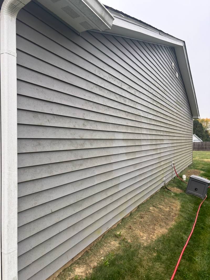 Gray vinyl siding with visible organic staining before washing